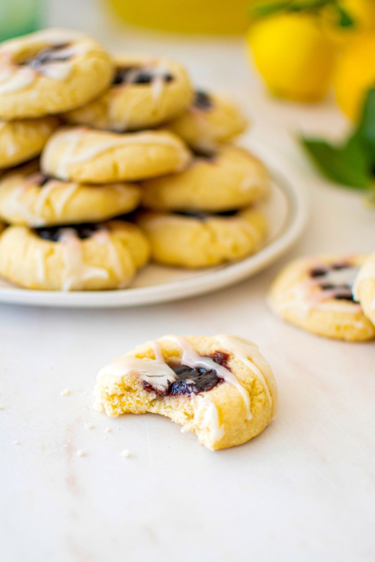 blackberry lemonade thumbprint cookie with glaze sitting on marble counter with a bite taken out.