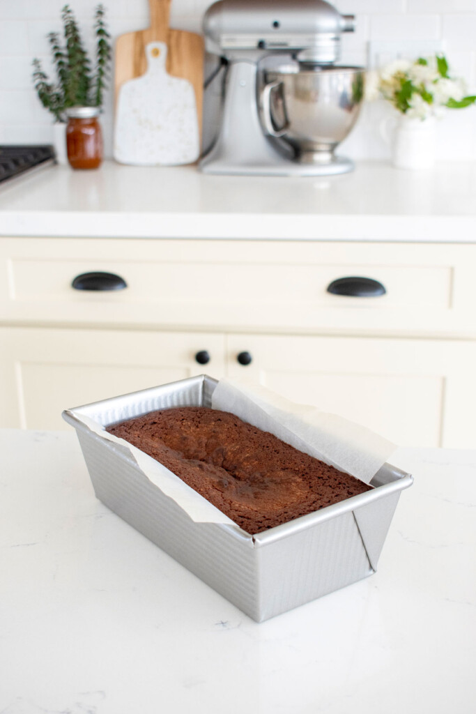 baked chocolate pound cake in a loaf pan on a white marble counter.