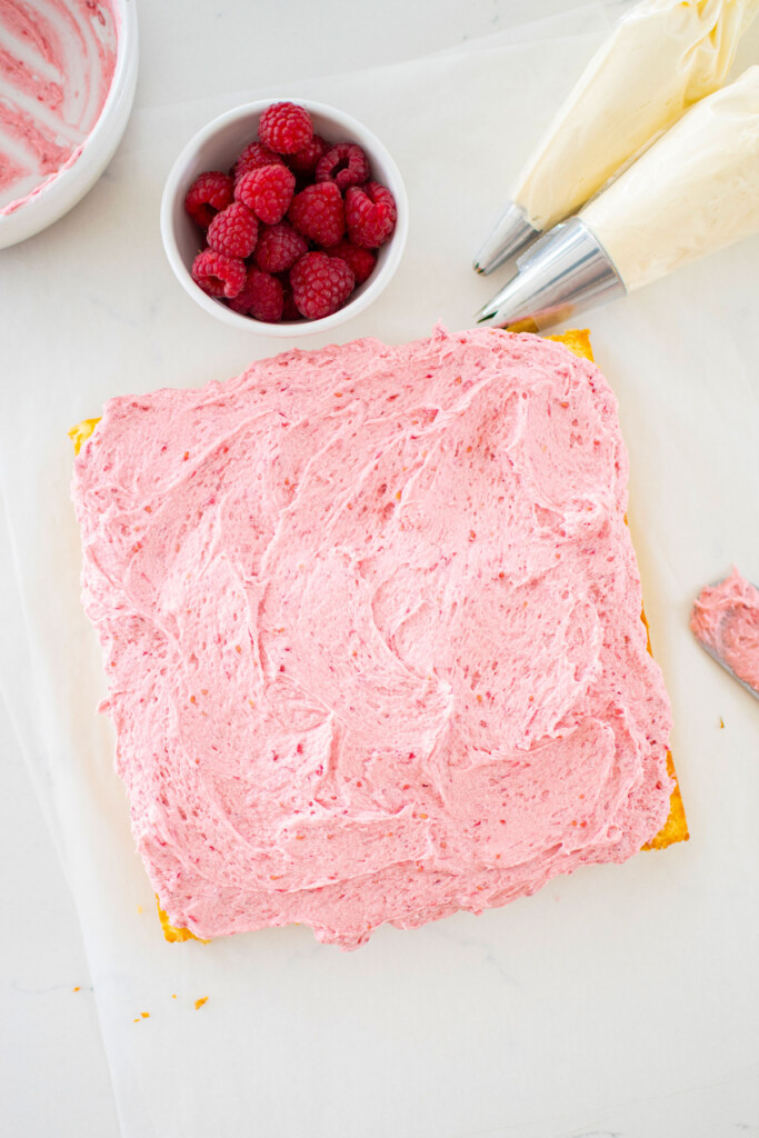 square lemon snack cake with fresh raspberry frosting spread evenly on top on a marble counter.