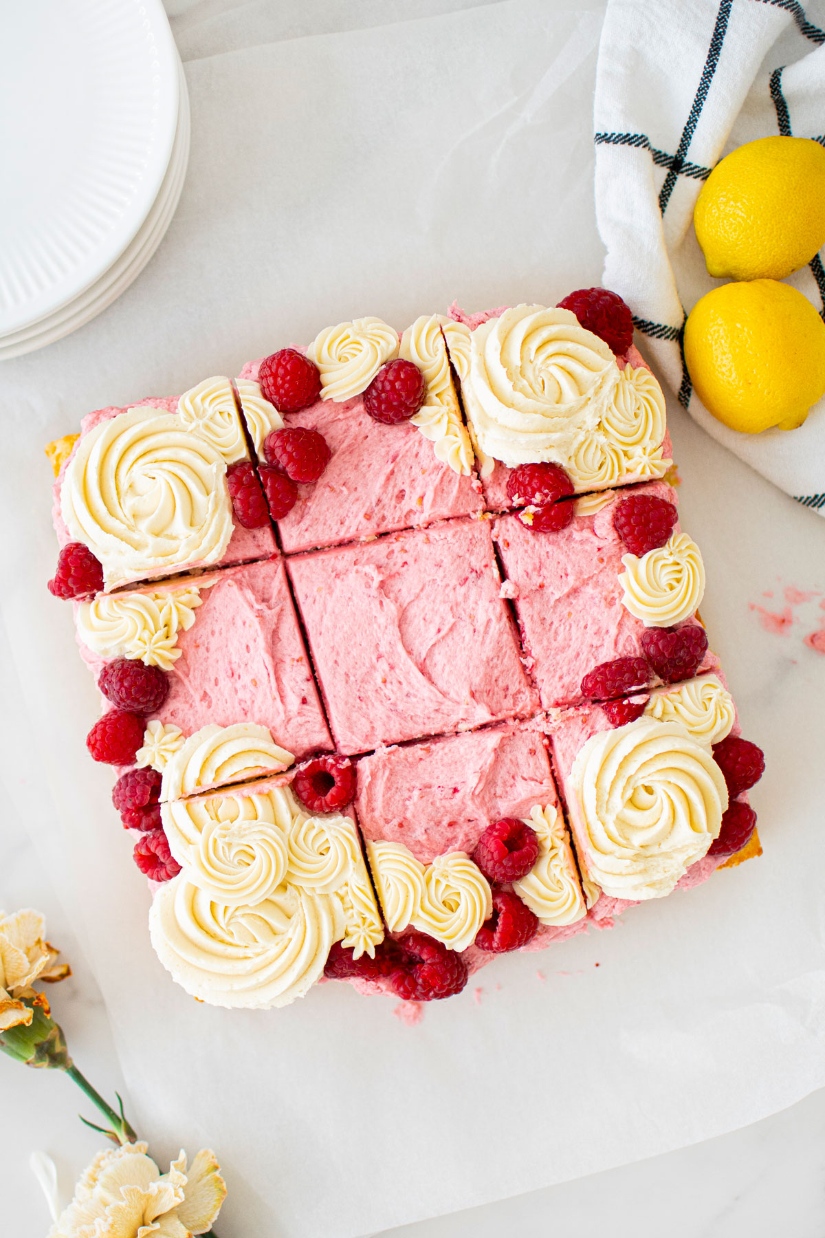 raspberry lemon snack cake cut into square slices on a marble counter.
