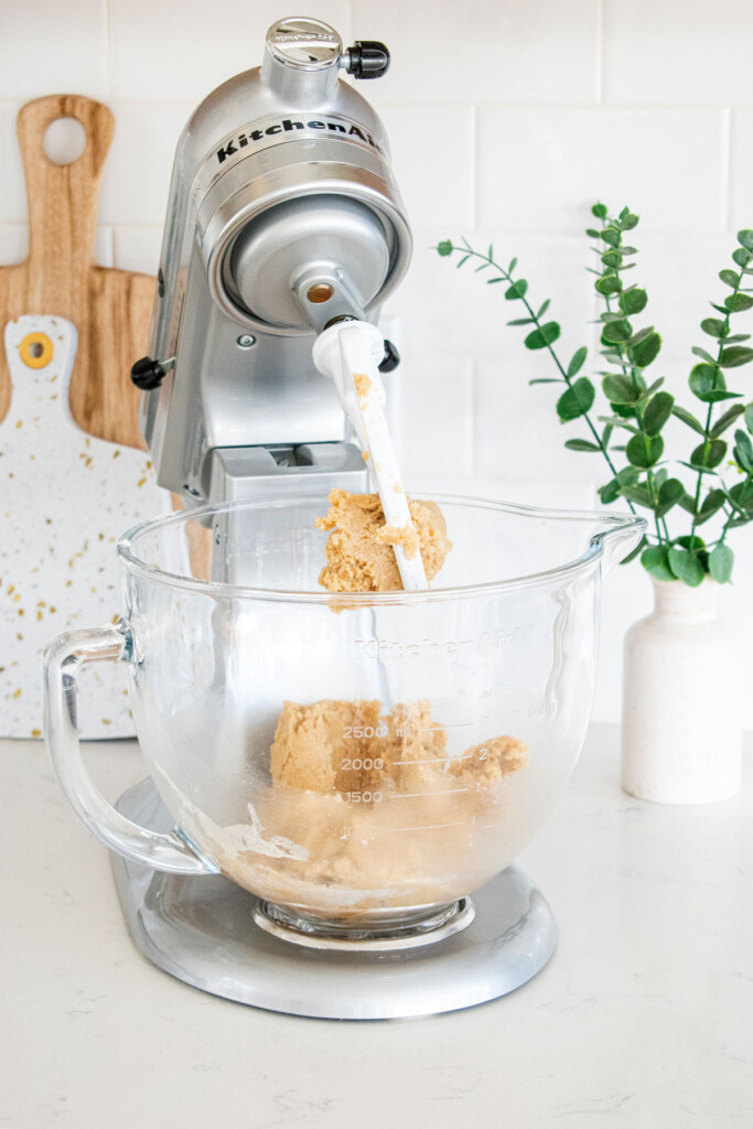 vegan blueberry bars dough in the bowl of a stand mixer on a white marble counter.