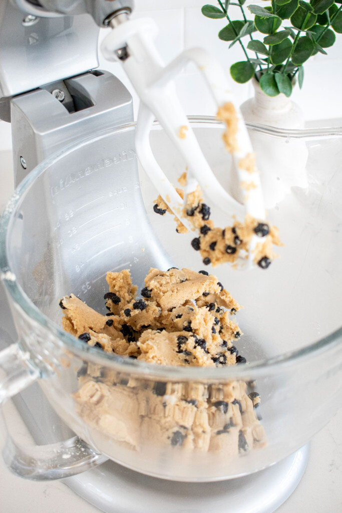 blueberry bars cookie dough in the bowl of a stand mixer on a white marble counter.