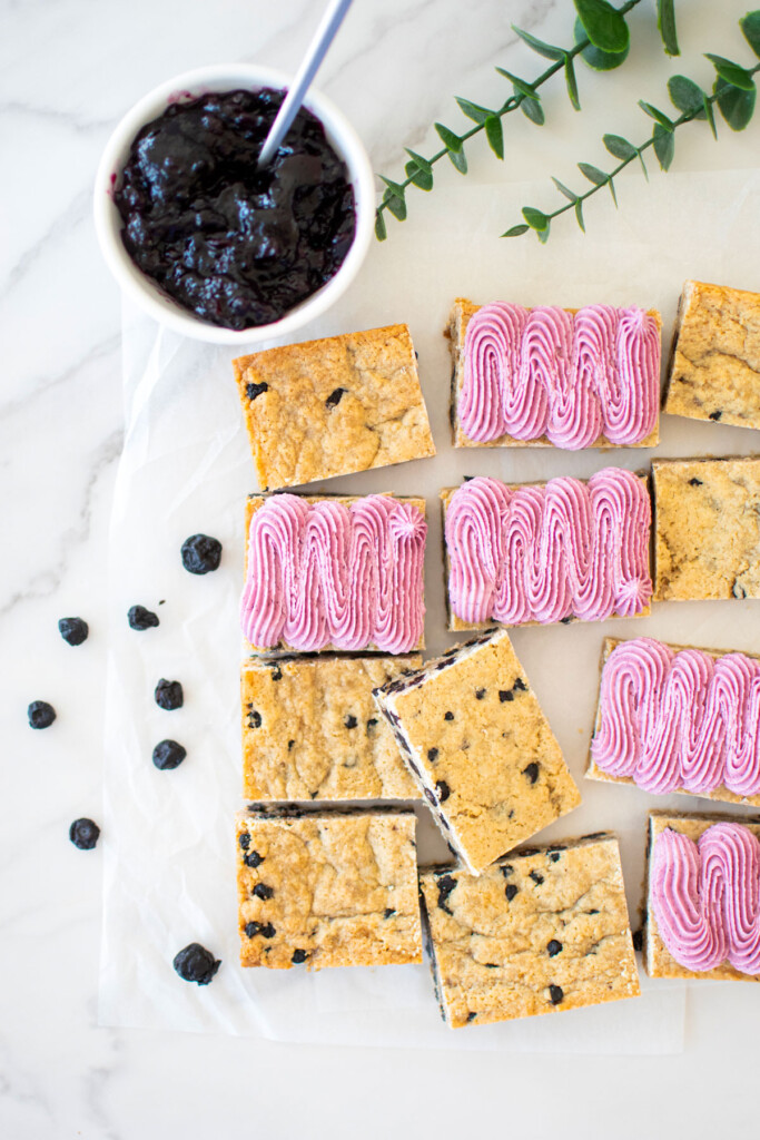 vegan blueberry bar with frosting on a white marble counter.