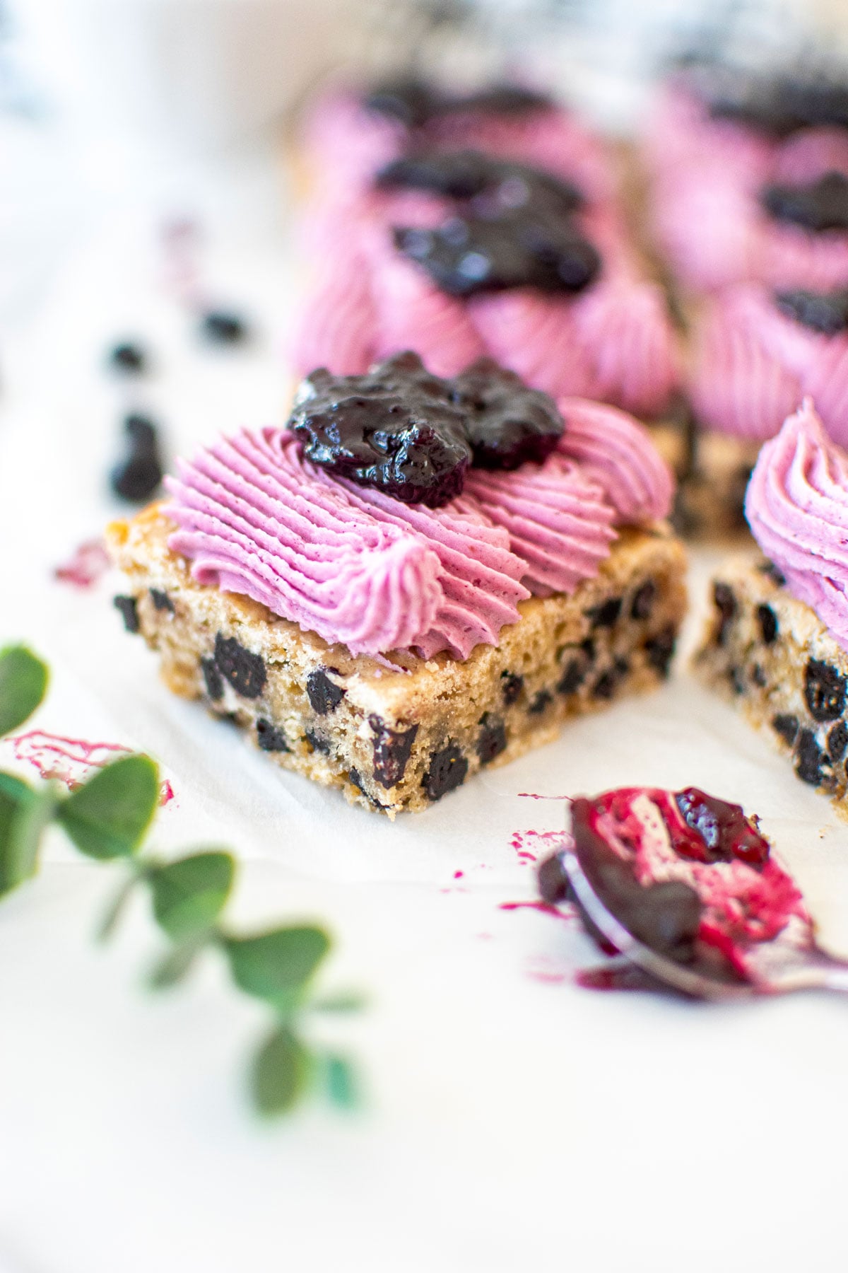 vegan blueberry bar with frosting and blueberry jam on a white marble counter.
