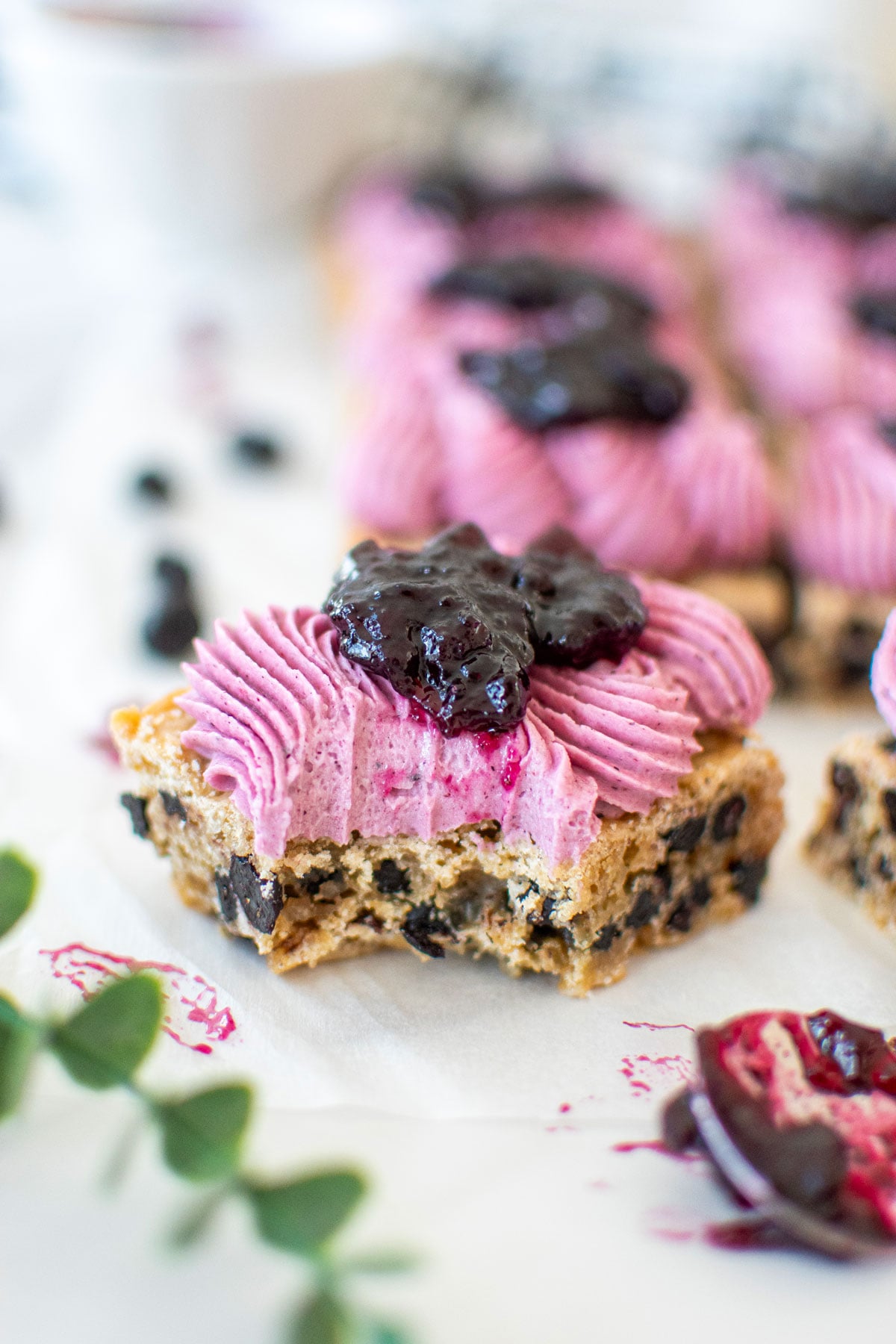 vegan blueberry bar with frosting and blueberry jam with a bite taken out on a white marble counter.