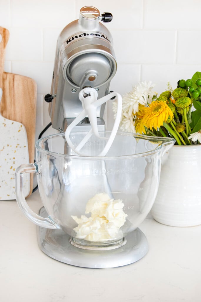 vegetable shortening in a stand mixing bowl on a white marble counter with a vase of flowers.
