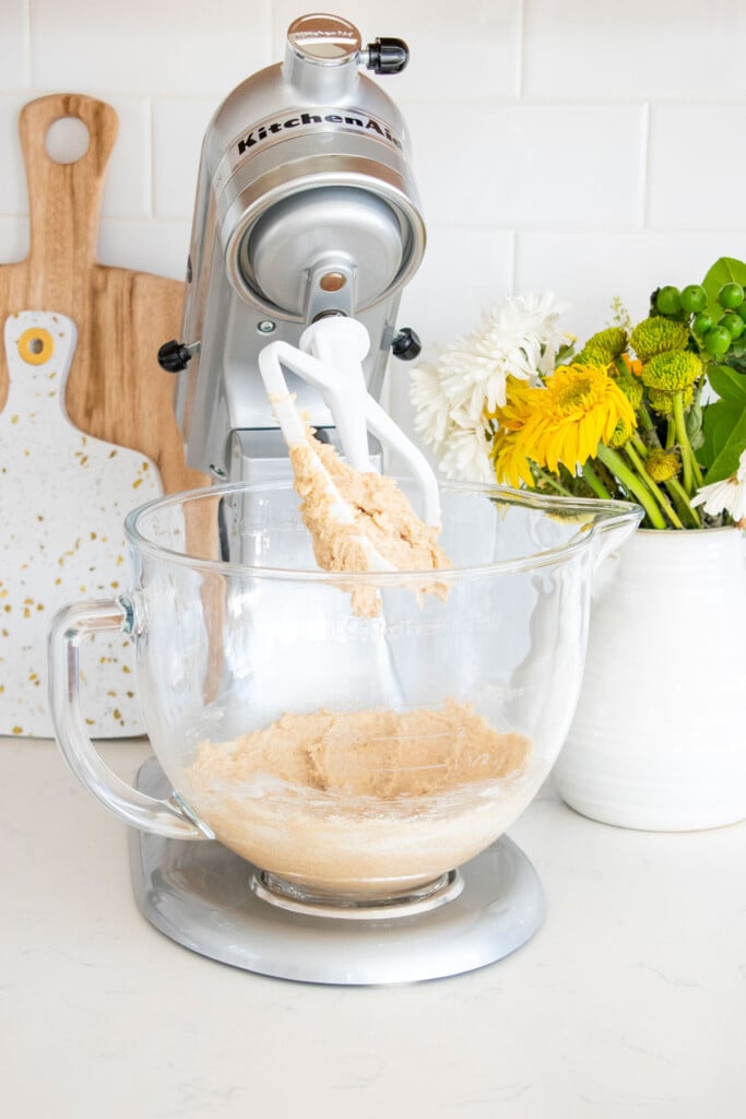 creamed shortening and sugar in a stand mixer on a marble counter with a vase of flowers.