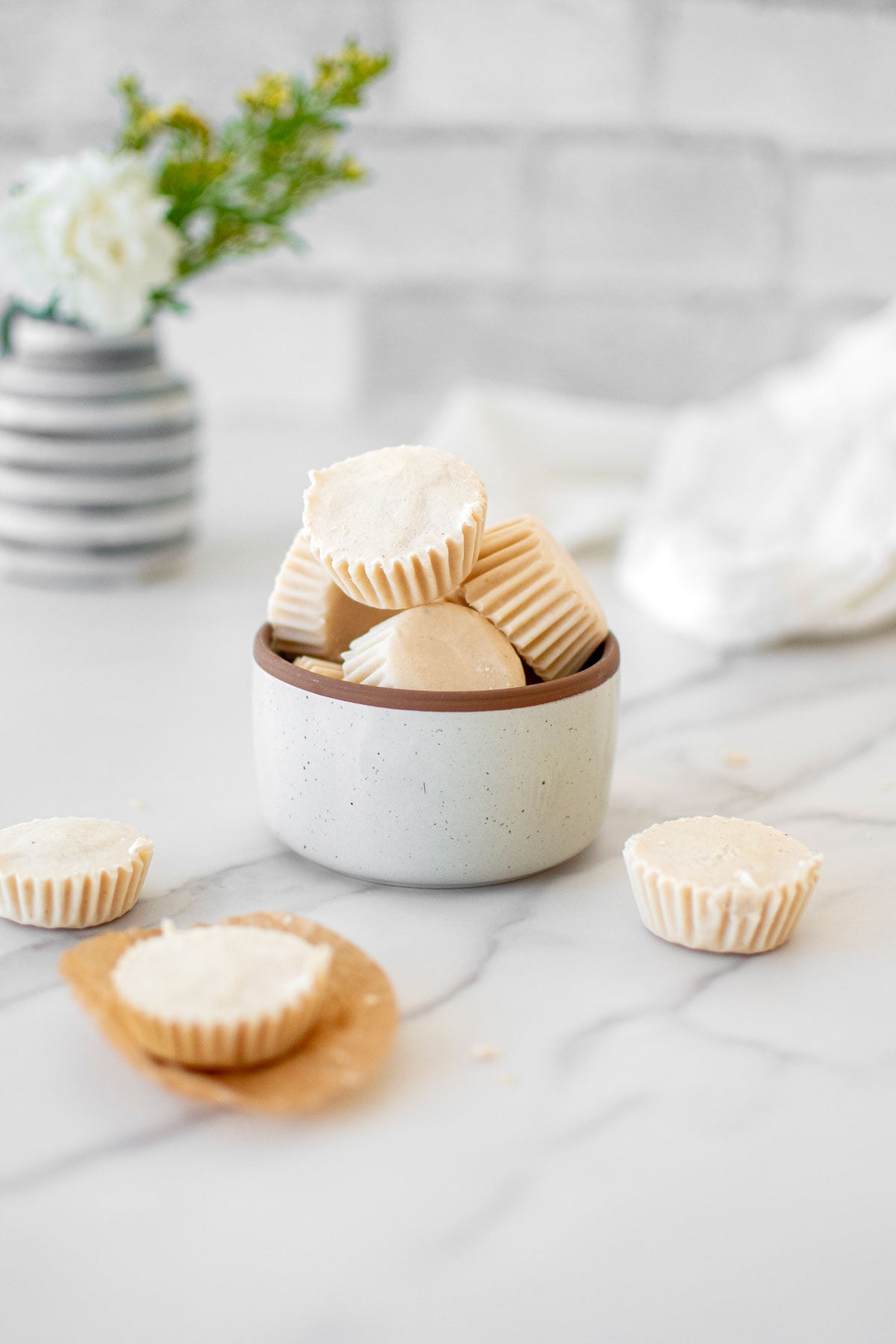 frozen peanut butter dog treats in a small gray bowl on a white marble countertop.