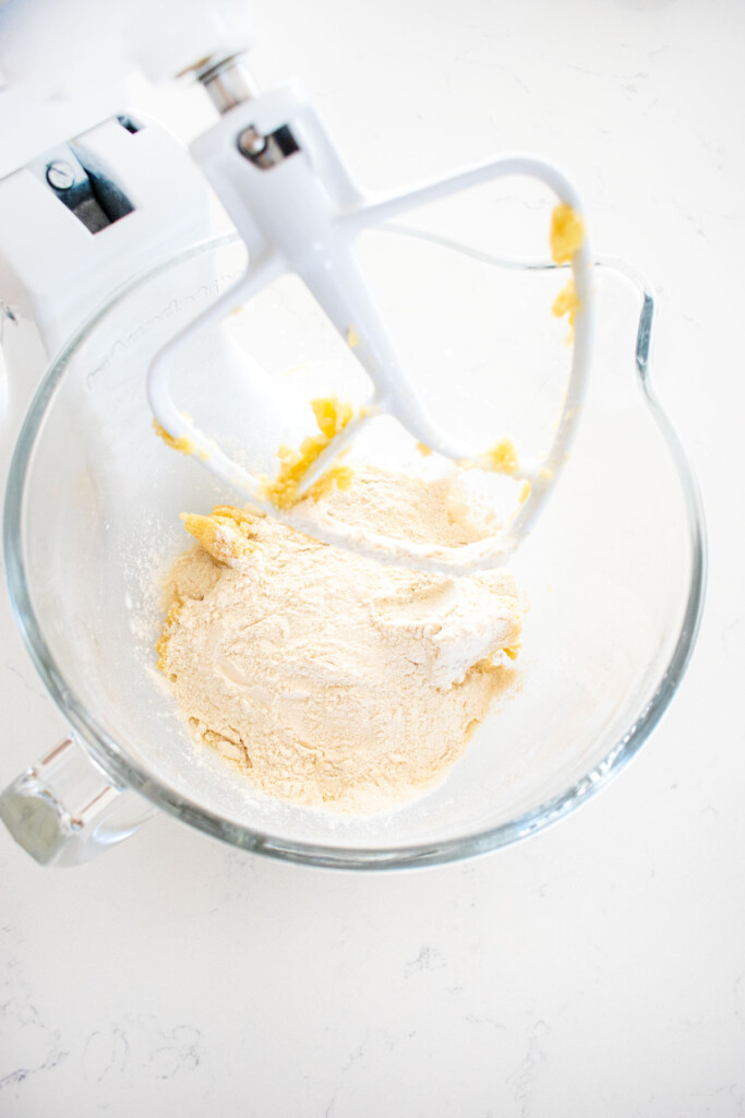 ingredients for eggless sprinkle cookies in a glass mixing bowl on a white marble counter.