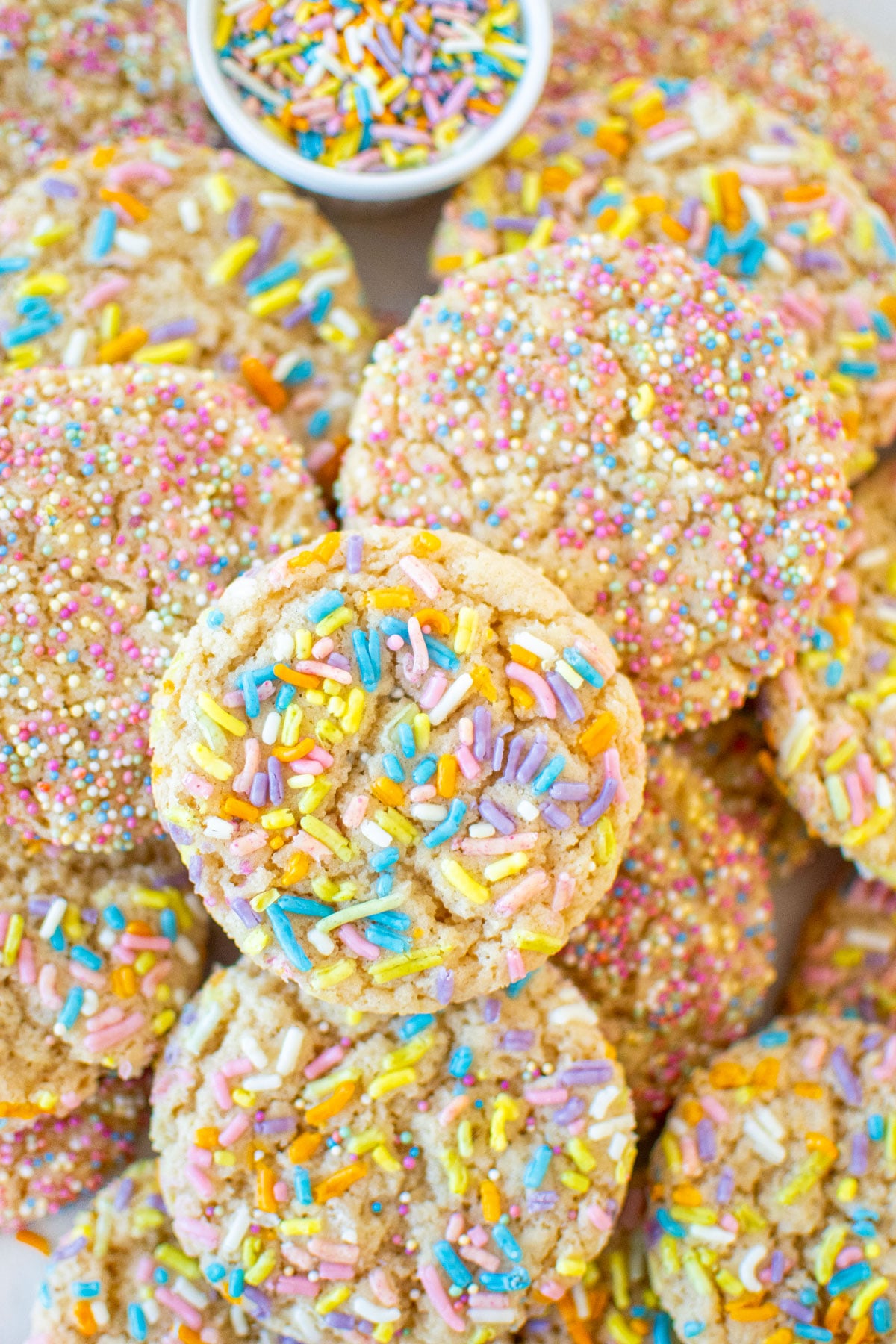 eggless sprinkle cookies in a pile on a baking sheet.