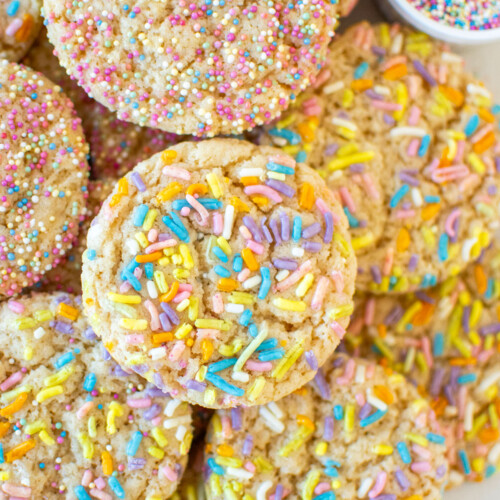 eggless sprinkle cookies in a pile on a baking sheet.