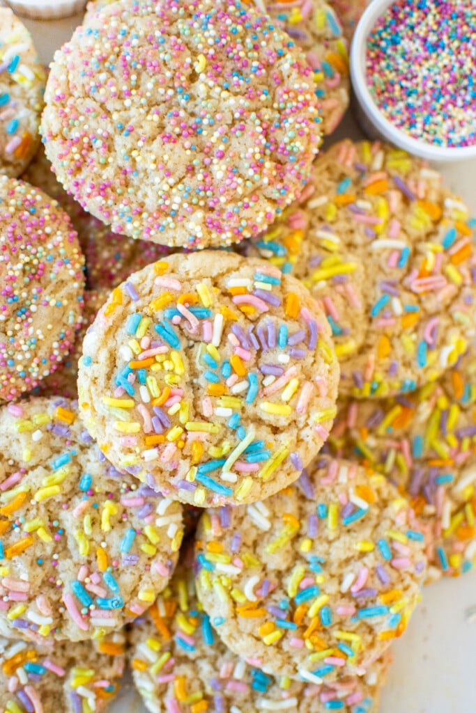 eggless sprinkle cookies in a pile on a baking sheet.