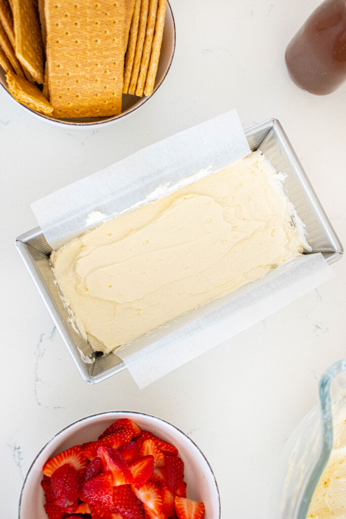 whipped cream spread evenly into a 1 pound loaf pan on a white marble counter.