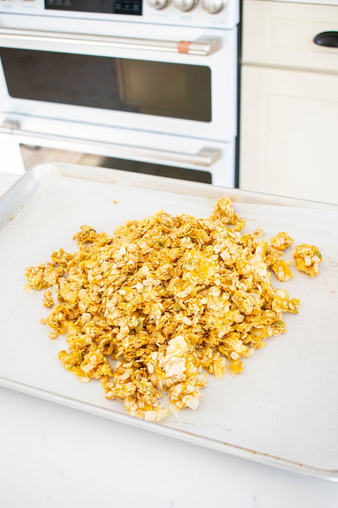 pumpkin granola for dogs being spread onto a baking sheet.