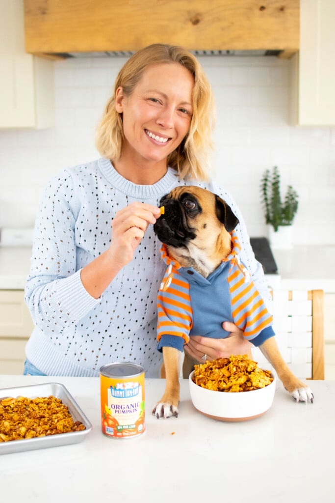 woman and pug in kitchen, woman feeding pug pumpkin granola for dogs.