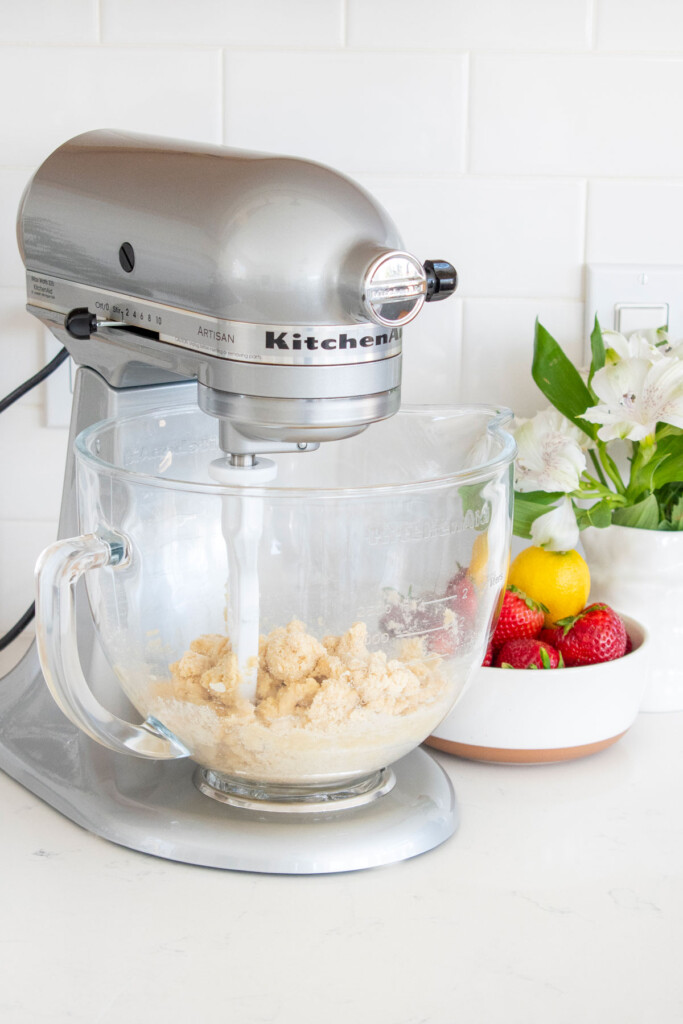sourdough strawberry pop tart dough being mixed in a mixer on a white marble countertop.