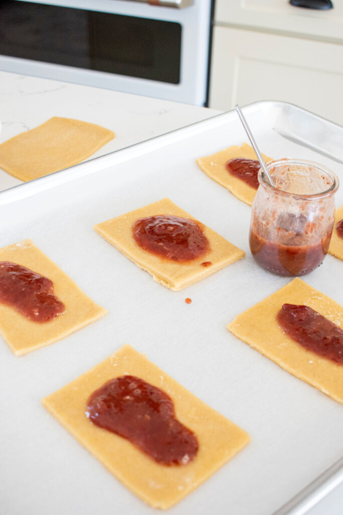 sourdough strawberry pop tart dough squares on a baking sheet with strawberry filling.
