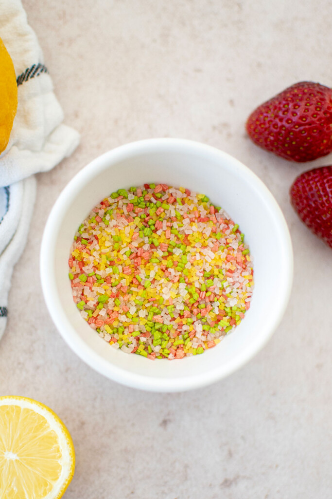 a small bowl of naturally colored decorating sugars on a light pink background. 