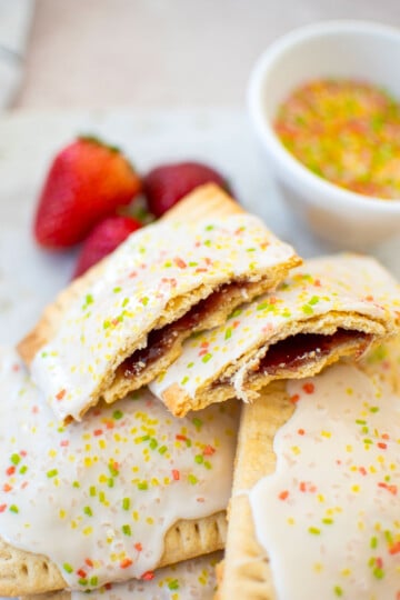 sourdough strawberry pop tart cut in half on a plate with fresh strawberries.