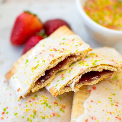 sourdough strawberry pop tart cut in half on a plate with fresh strawberries.