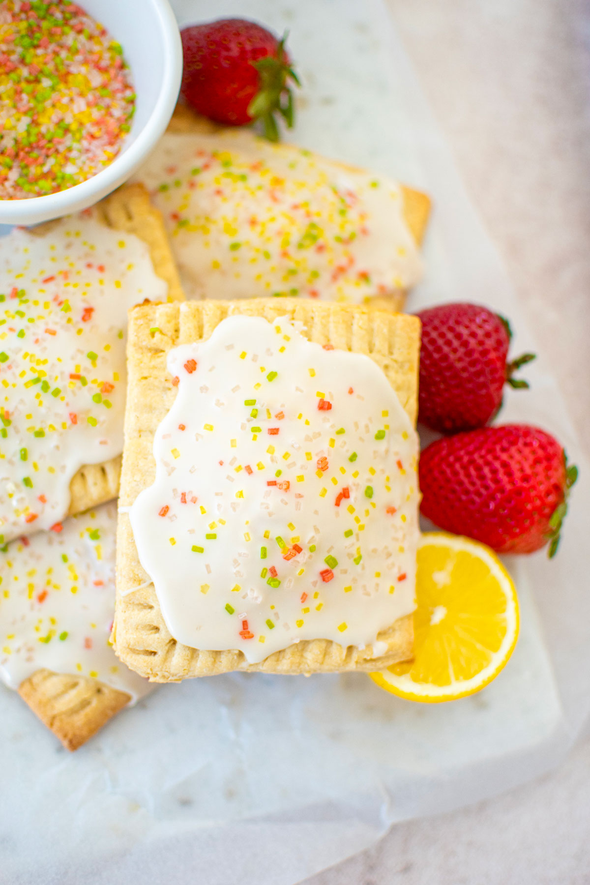 sourdough strawberry pop tarts on a marble board with fresh strawberries and lemon.