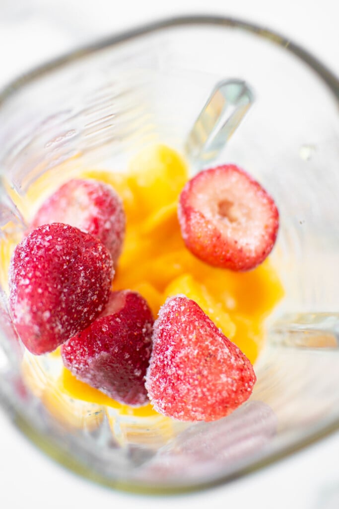 frozen strawberries, mango, and pineapple in a blender.