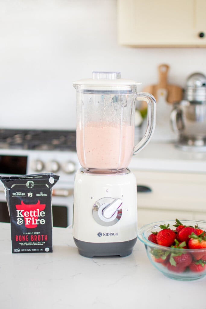 tropical bone broth smoothie in a blender on a kitchen counter.