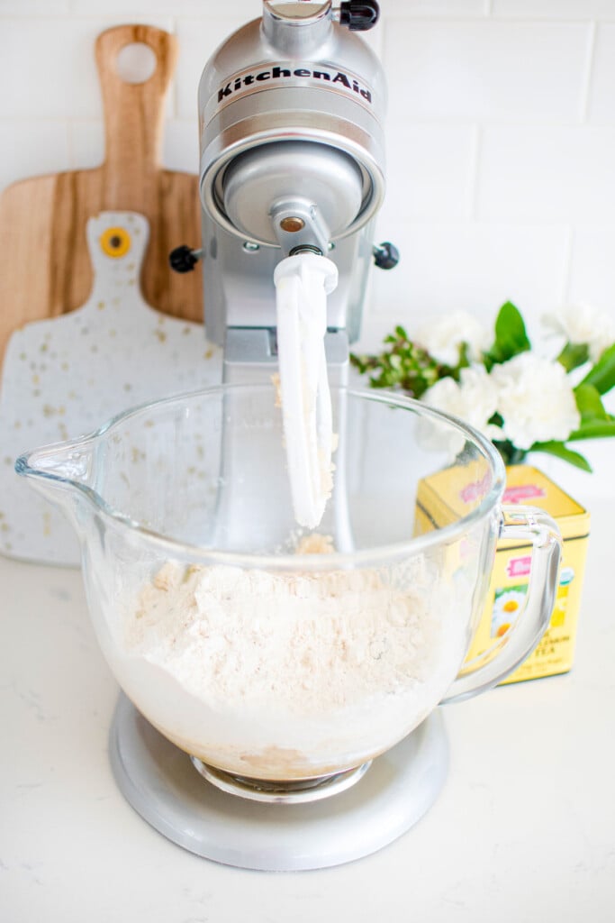 dry ingredients being added to vegan lemon chamomile tea cake batter in a glass mixing bowl.