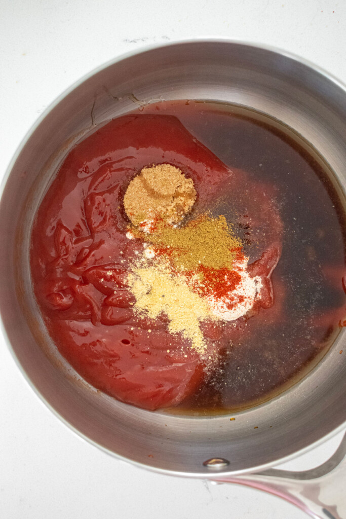 ingredients for homemade bbq sauce with bone broth in a pot on a white countertop.