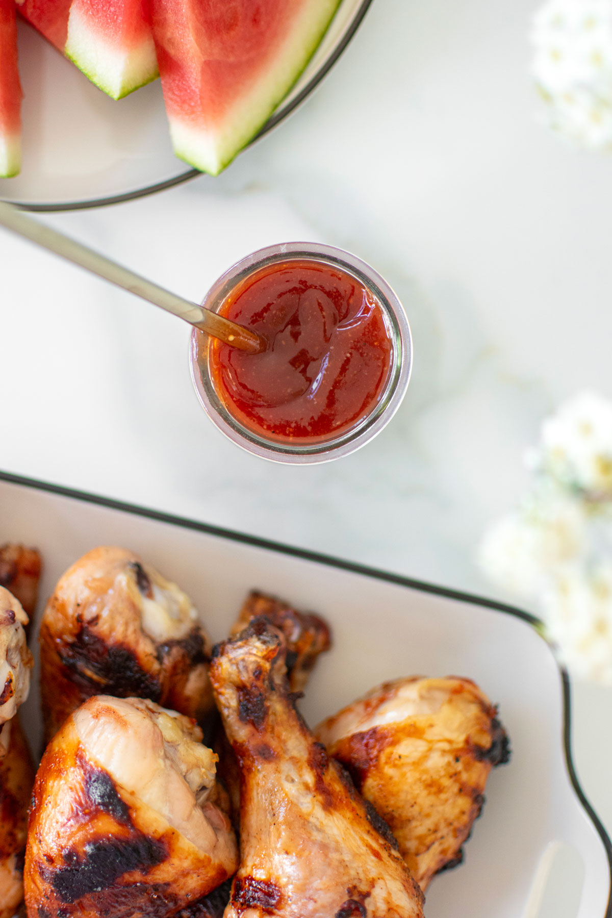 homemade bbq sauce with bone broth in a glass jar with a spoon on a marble counter.