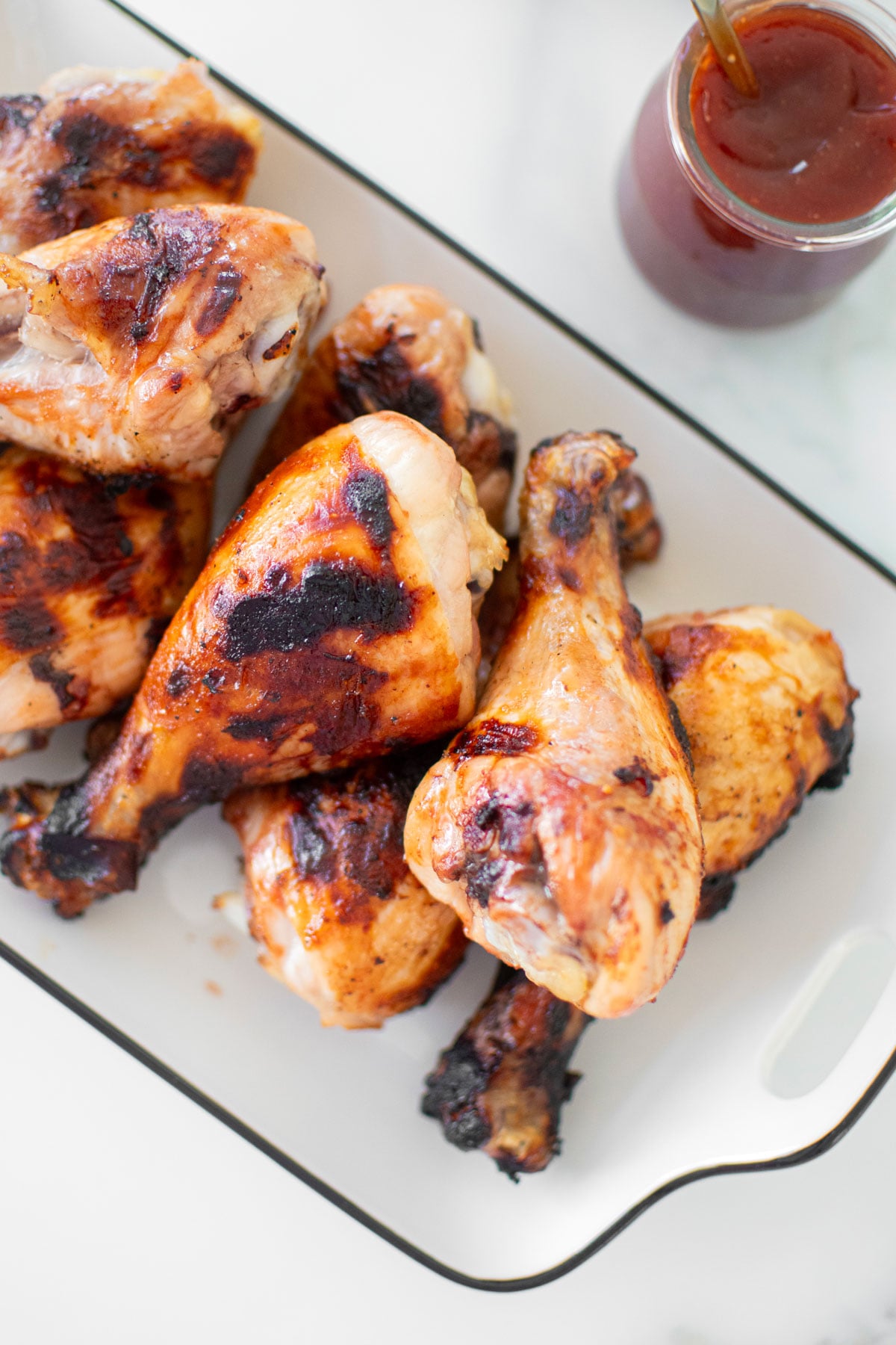 homemade bbq chicken on a platter on a white marble countertop.