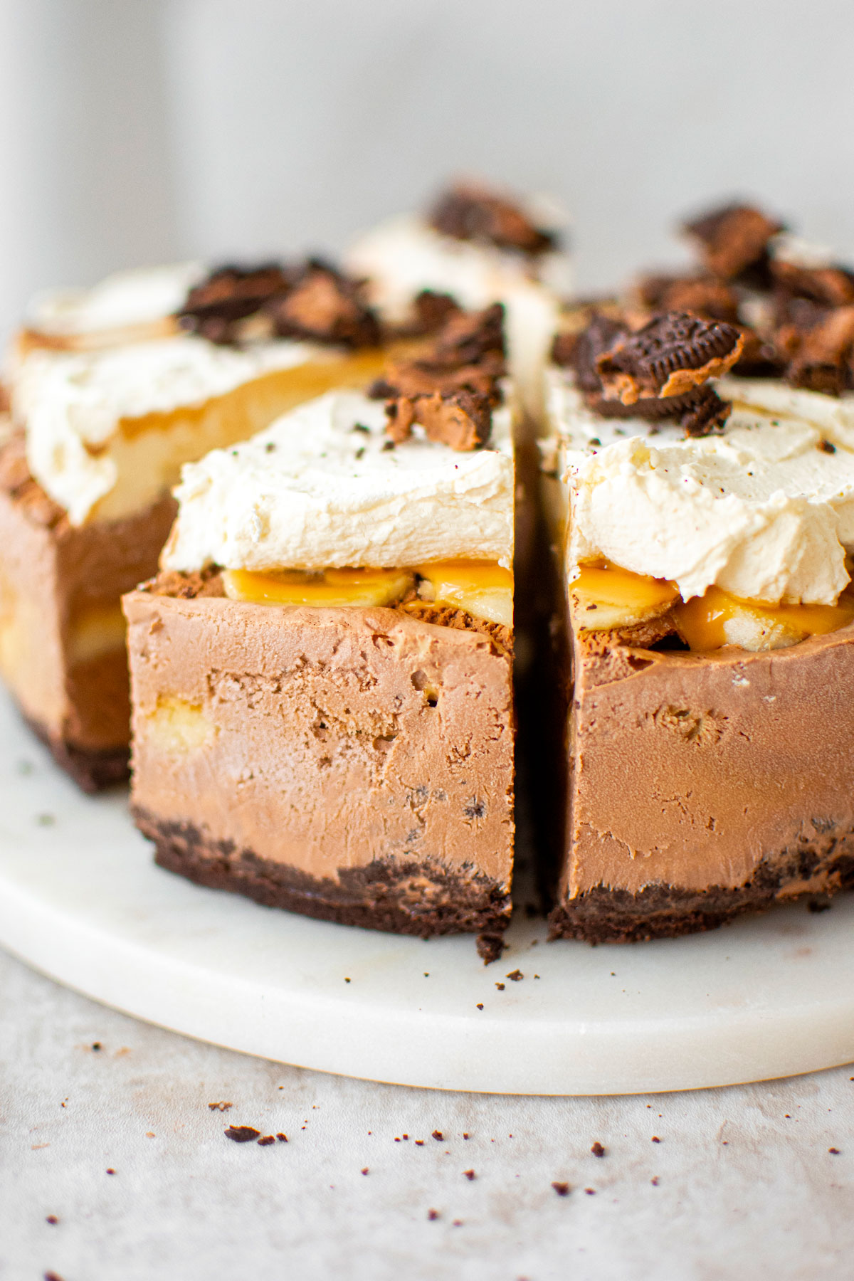 chocolate banana caramel ice cream pie cut into slices on a marble serving board.