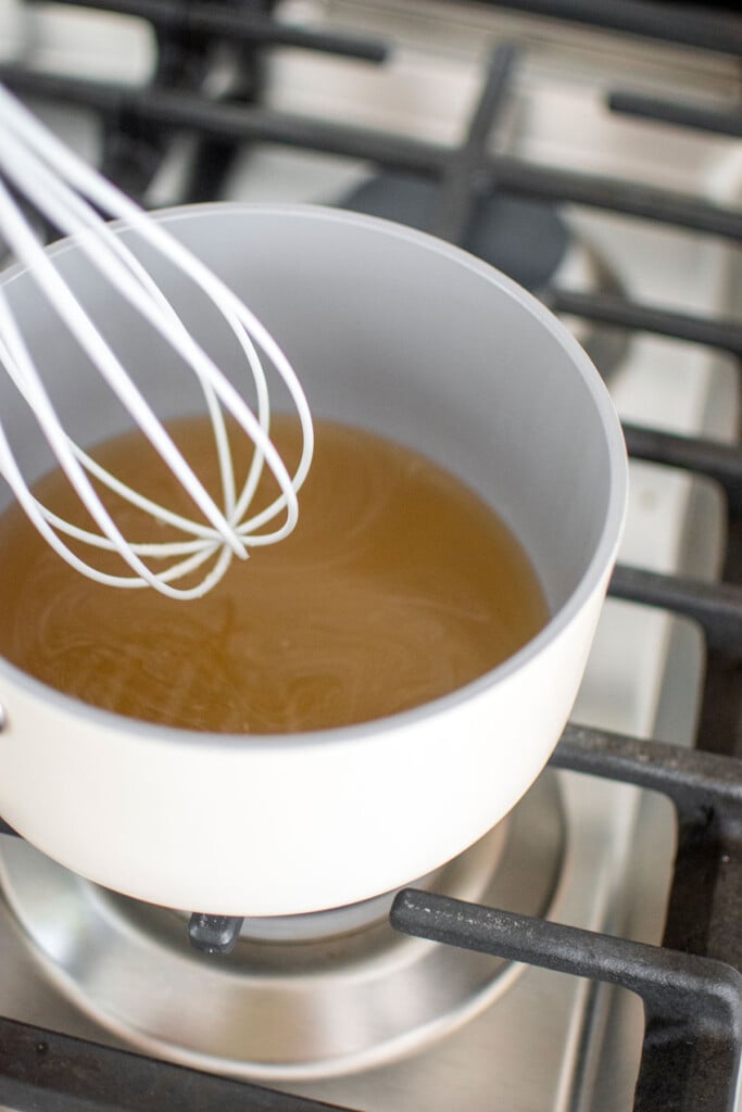simple syrup being made in a small pot on the stovetop.