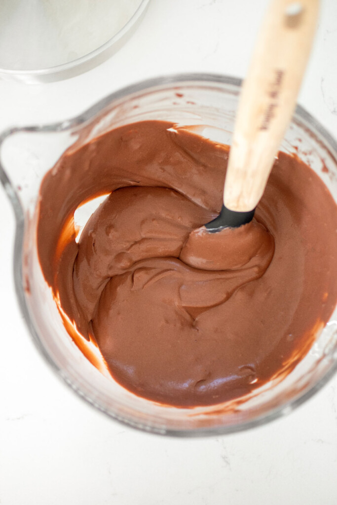 chocolate ice cream base in a glass mixing bowl on a white countertop.