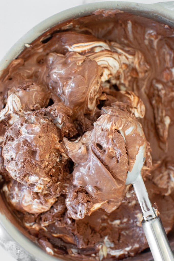 organic rocky road ice cream being scooped out of a pan with an ice cream scoop.