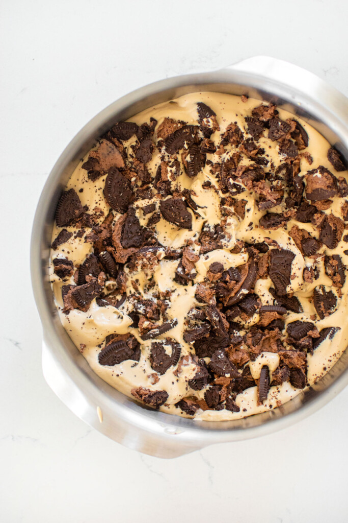 cookies and cream coffee ice cream in a cake pan on a white marble counter.