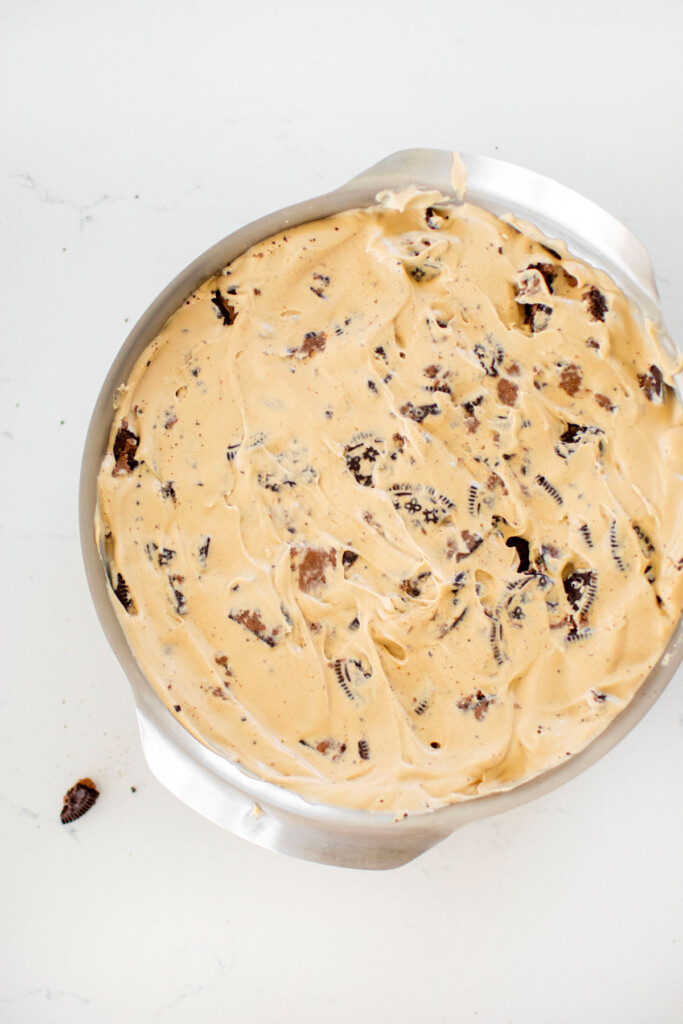 cookies and cream coffee ice cream in a cake pan on a white marble counter.