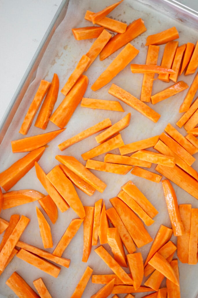 sweet potato fries on a baking sheet on a marble countertop.