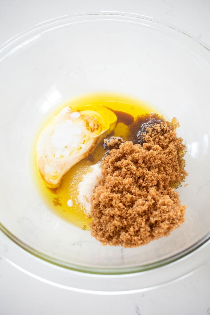wet ingredients for olive oil strawberry blondies in a glass mixing bowl on a white marble counter.
