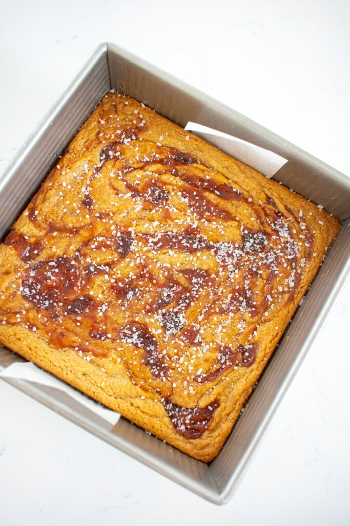 strawberry olive oil brownies in a square baking pan on a white marble counter.