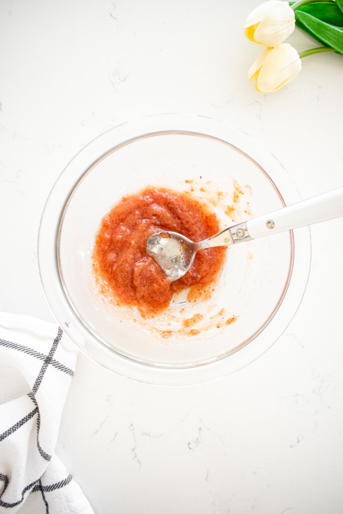 glass mixing bowl with strawberry jam and cornstarch mixed together.
