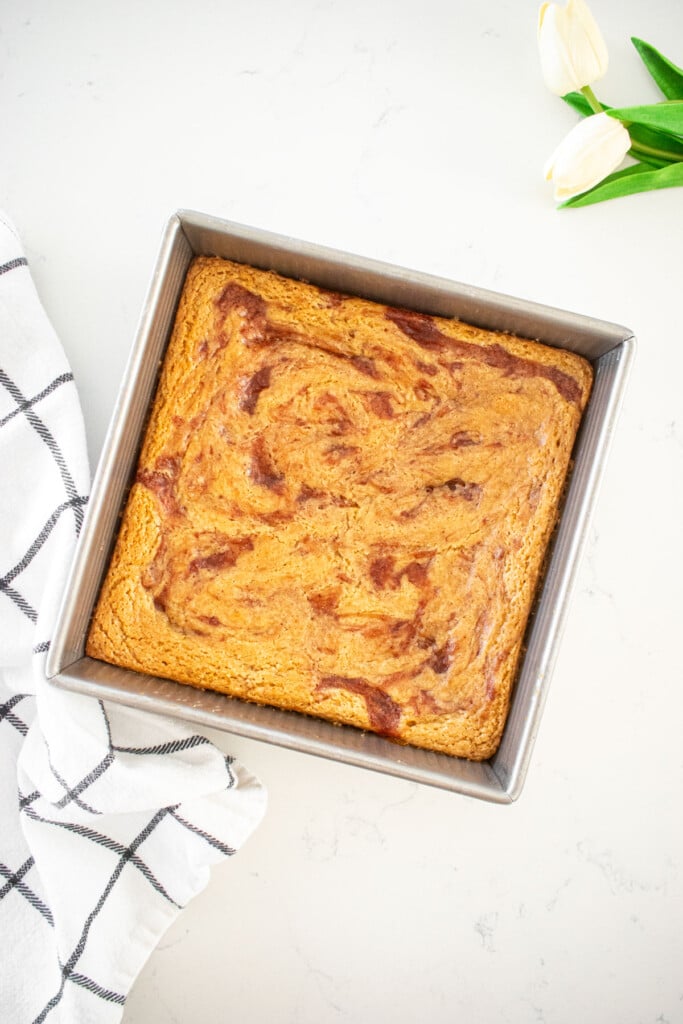 baked olive oil strawberry blondies in a square baking pan on a marble counter.