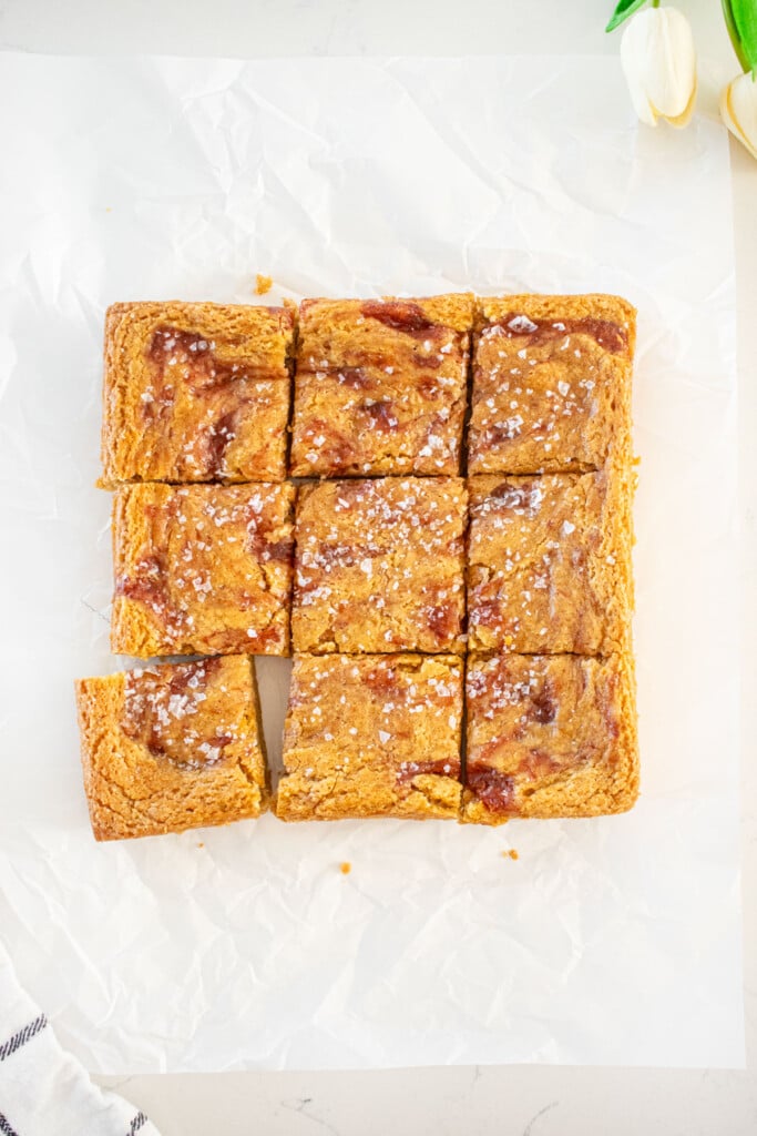 olive oil strawberry blondies with flaky sea salt cut into squares on a white marble counter.
