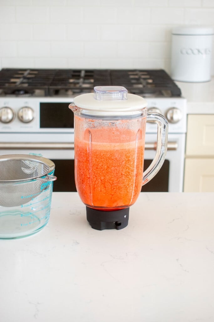 glass blender with blended strawberry limeade on the kitchen counter.