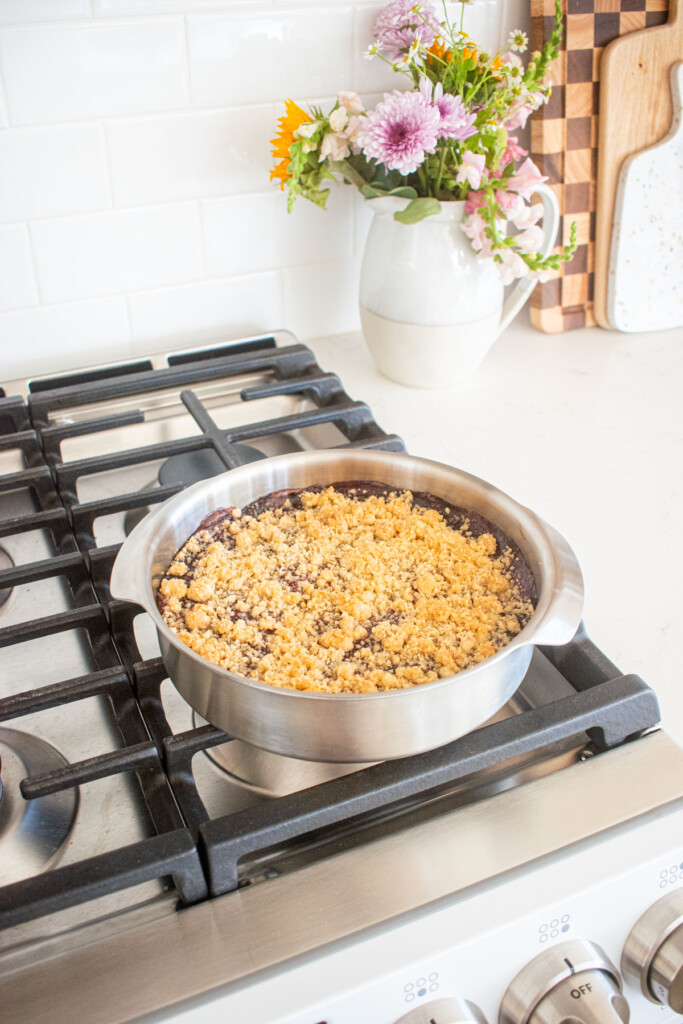 cherry pie bars in a round cake pan chilling on top of an oven.