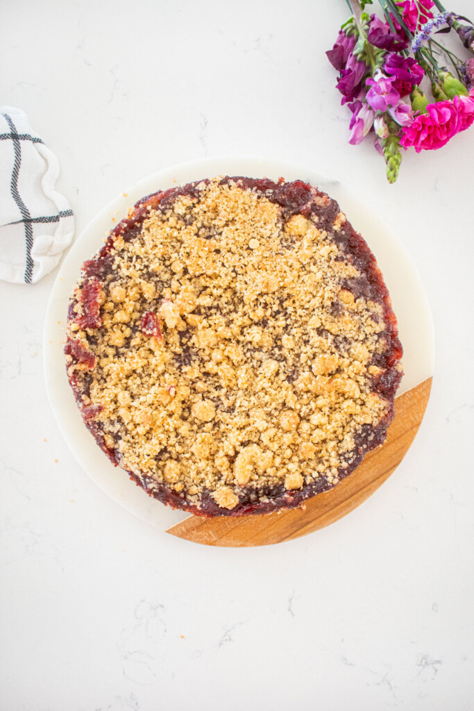 cherry pie bars on a round serving platter on a white marble counter with fresh flowers.