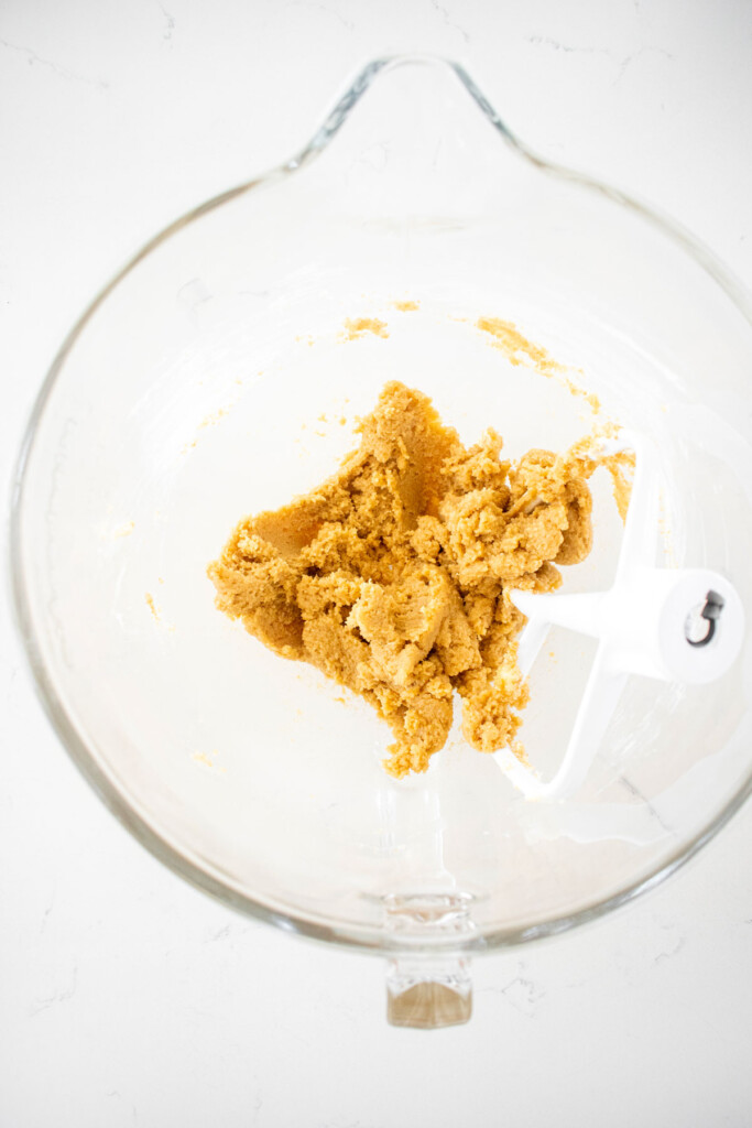 creamed butter and sugar in a glass mixing bowl on a marble counter.