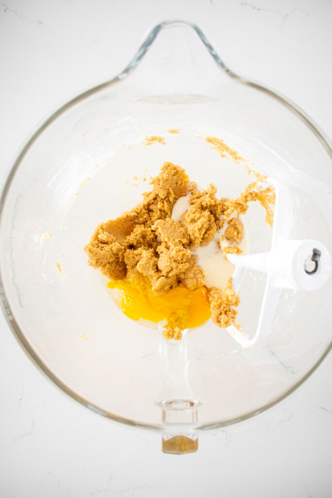 creamed butter and sugar with egg in a glass mixing bowl on a marble counter.