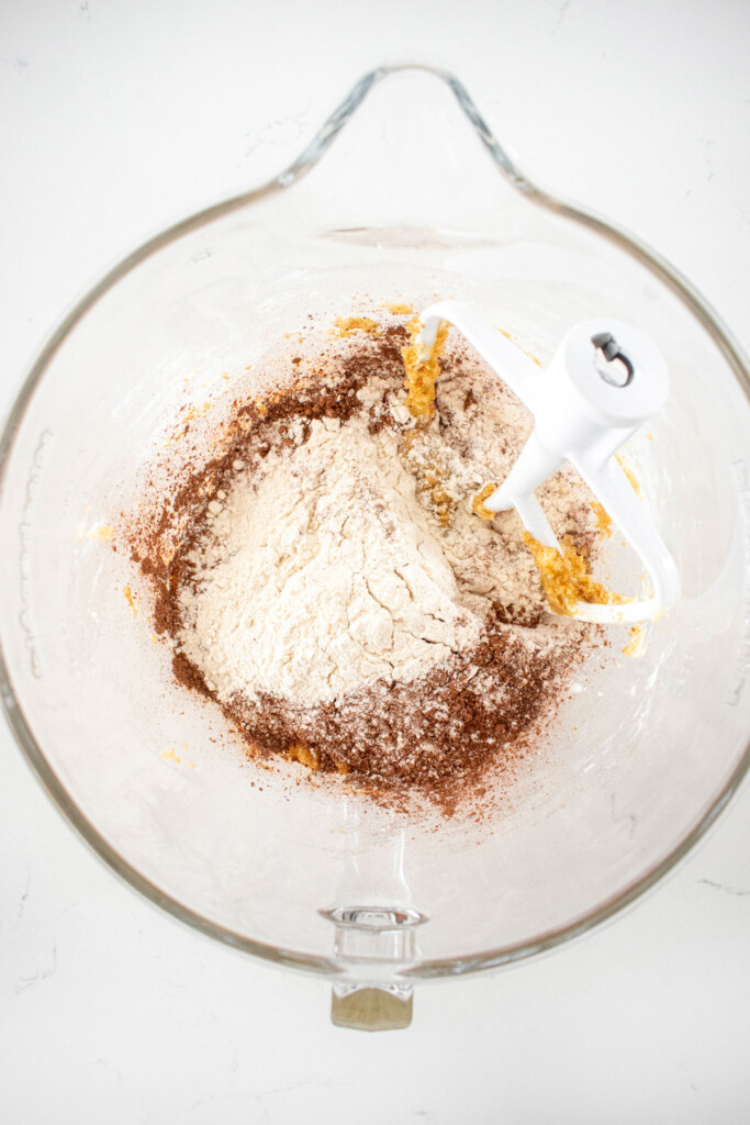 ingredients for chocolate espresso cookies in a glass mixing bowl on a white marble counter.