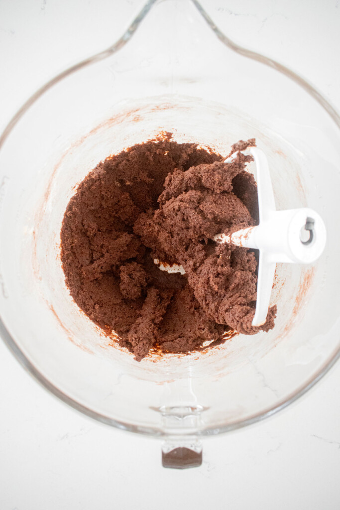 chocolate espresso cookie dough in a glass mixing bowl on a marble counter.
